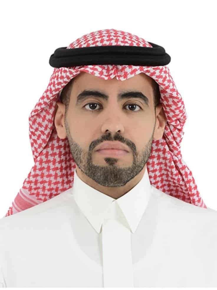 رجل سعودي يرتدي الزي التقليدي والشماغ مع نظرة مباشرة.